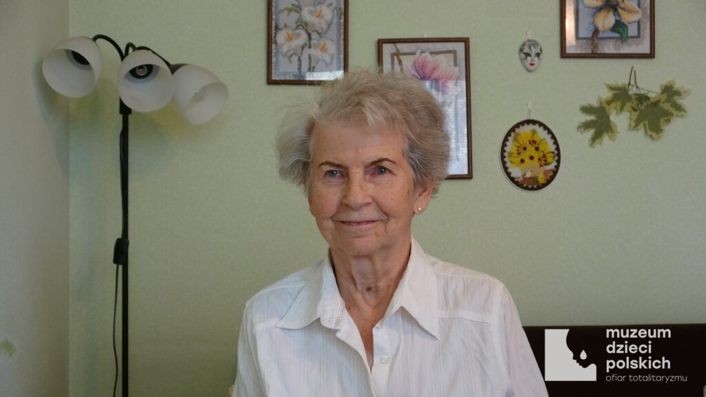 Współczesne zdjęcie Krystyny Złotowskiej wykonane w domu. Kobieta siedzi za stołem.