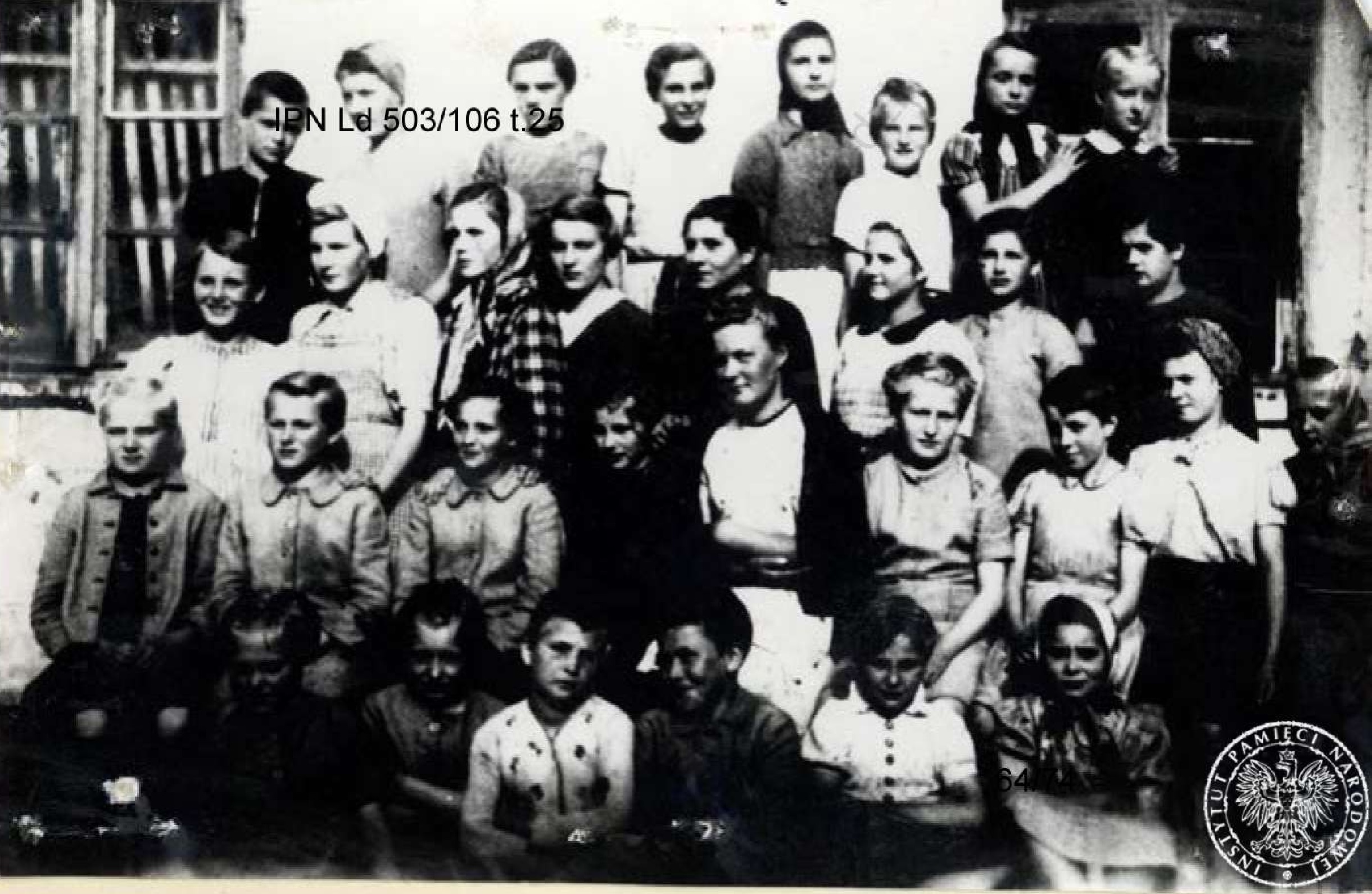 Zdjęcie grupowe. Więźniarki ustawione w czterech rzędach, pośrodku nadzorczyni.