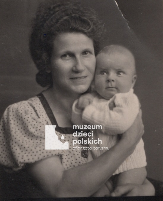 Zdjęcie portretowe, wykonane w atelier. Matka trzyma na rękach kilkuletnią córkę.