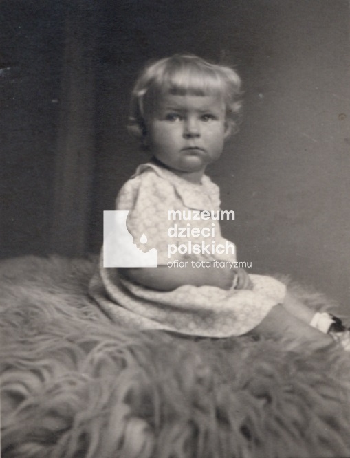 Zdjęcie portretowe, wykonane w atelier. Roczna dziewczynka w pozycji siedzącej.